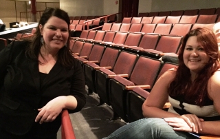 Two girls sitting in theatre chairs