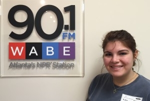 Kaley Lachey standing beside 90.1 WABE sign